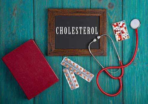 a board with 'cholesterol' written on it, along with a diary, stethoscope, and medicines kept around it